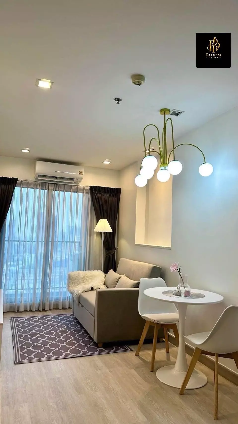 Green chandelier and city views highlight the furnished living room in this Casa Condo Asoke-Dindaeng unit