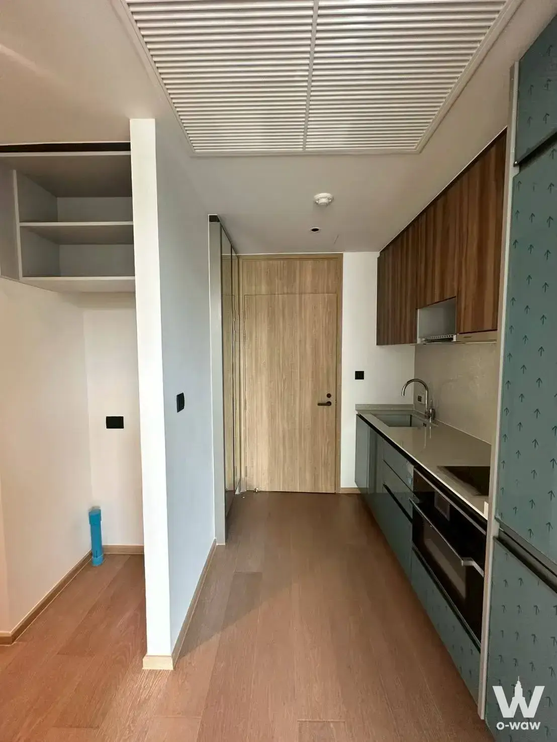Kitchen corridor in a 1-bed condo for rent at Chalermnit Art De Maison showing dark grey cabinets and walnut upper storage