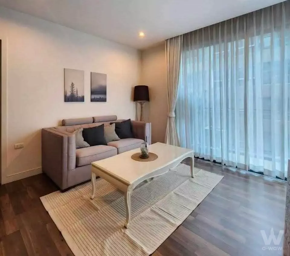 2-bed condo for rent in The Room Sukhumvit 62 living room with beige sofa and mid-floor city view