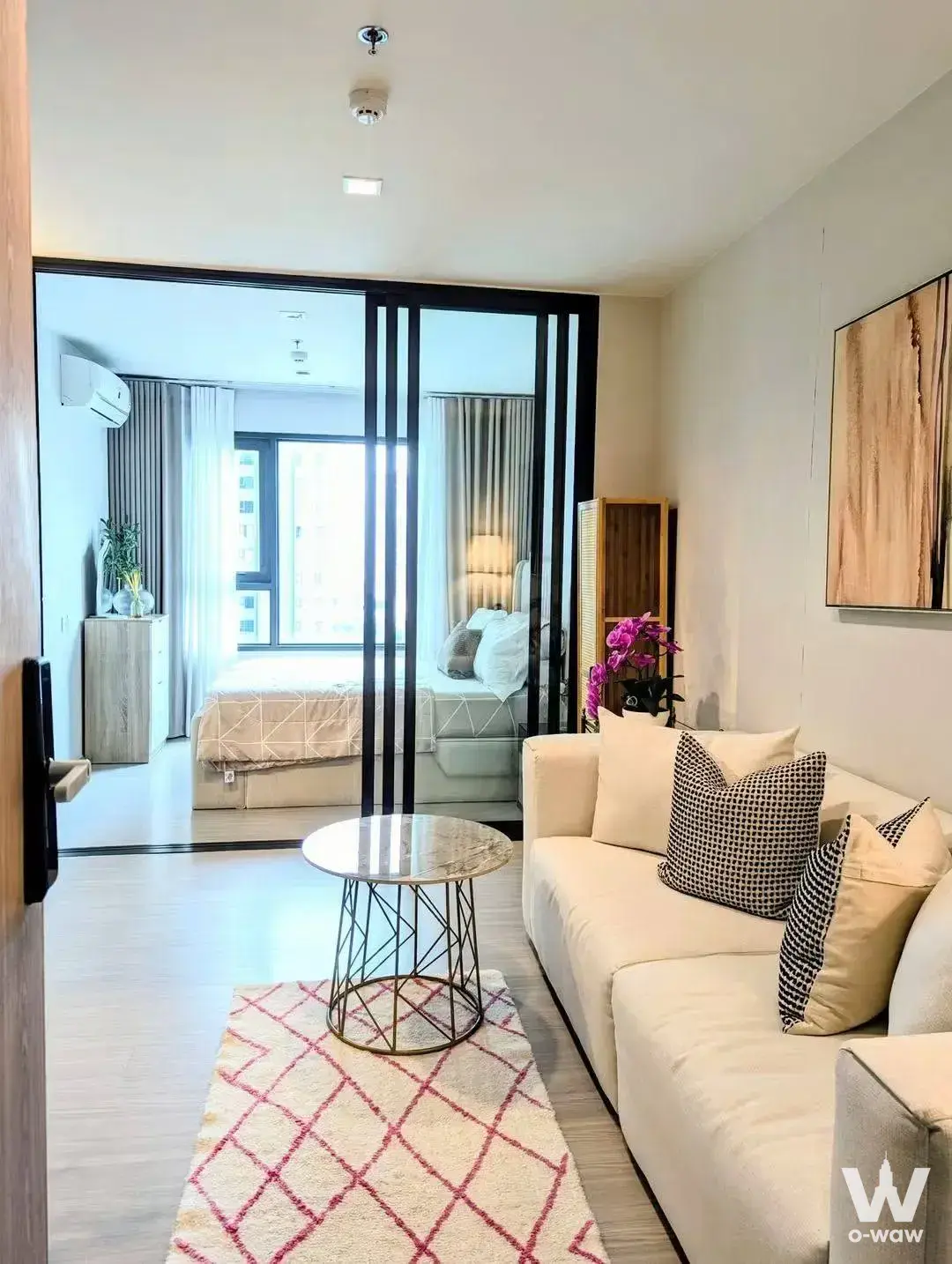 Living room in a Life Sathorn Sierra condo with a cream sofa, marble coffee table, and sliding glass partition