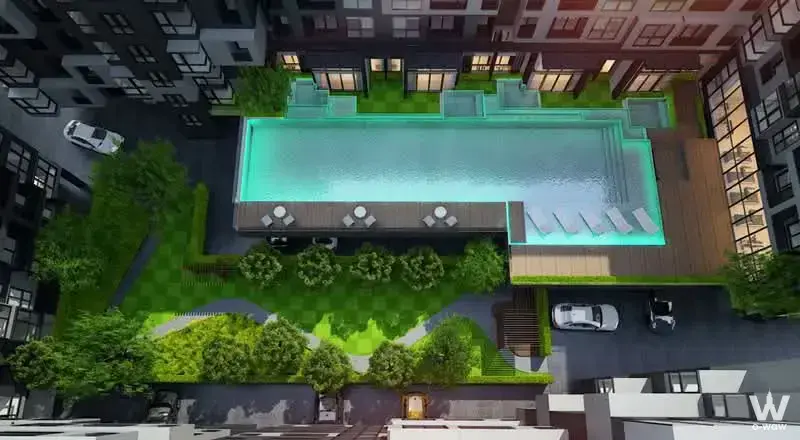 Aerial view of Rise Rama 9 rooftop pool deck with turquoise water, wooden decking, and surrounding greenery