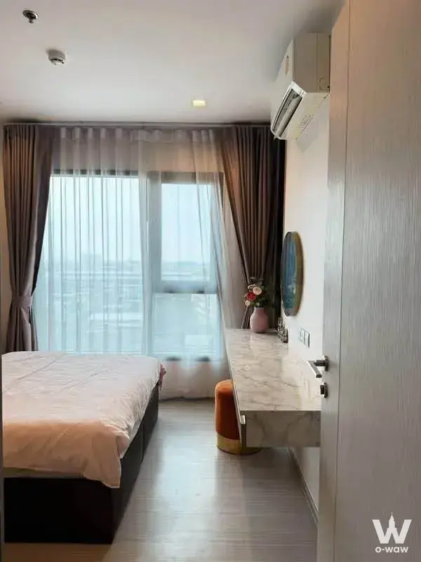 Modern bedroom in Life Sukhumvit 62 condo featuring dark wood bed frame, floating desk, and city view