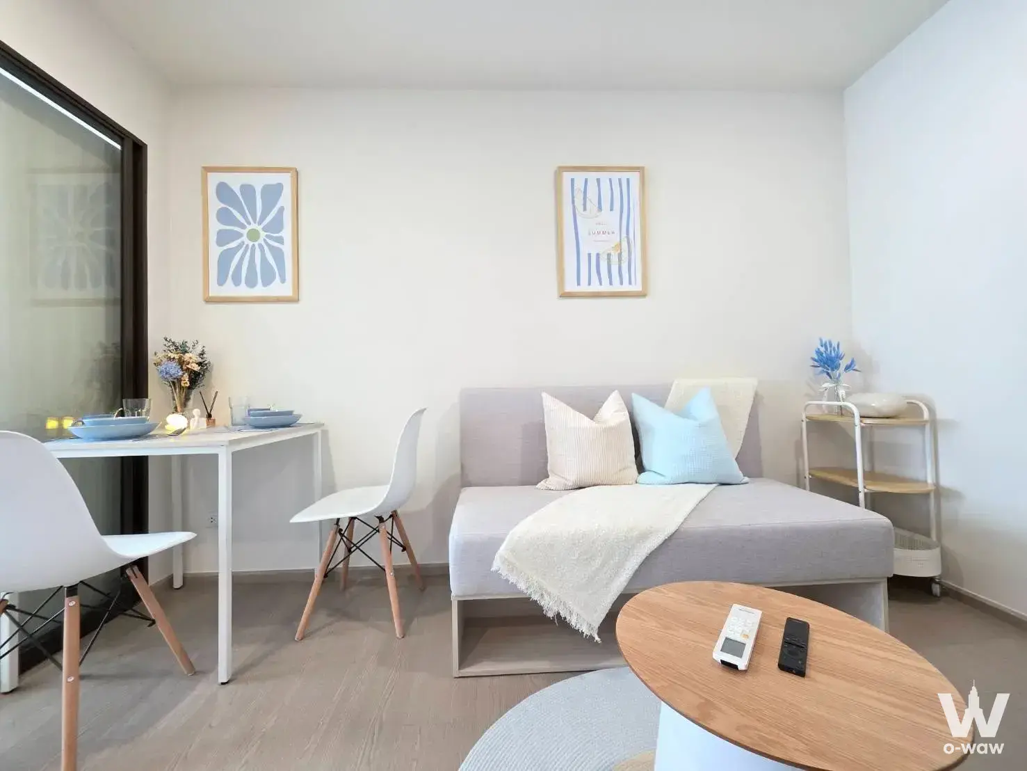 Grey sofa and dining nook with blue accents in a bright 1-bed condo for rent at GOOD Day Sukhumvit 93