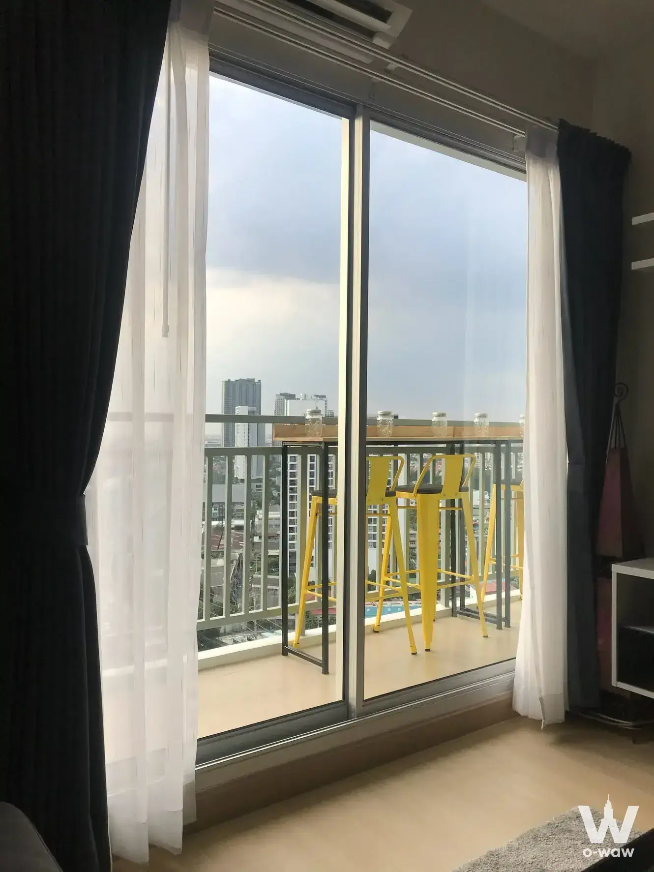 2-bed condo for rent in Supalai Park Talat Phlu Station offering balcony access with yellow bar stools and city skyline views