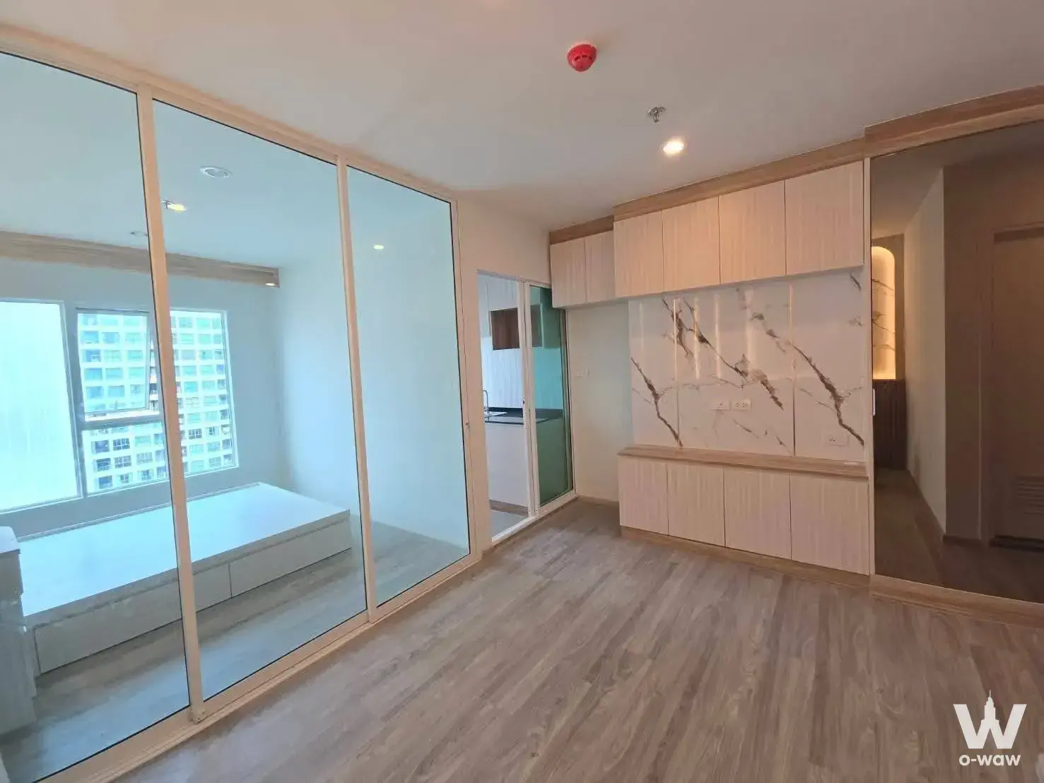 Unfurnished living room with built-in wood cabinets in a Regent Home Bangna condo for rent