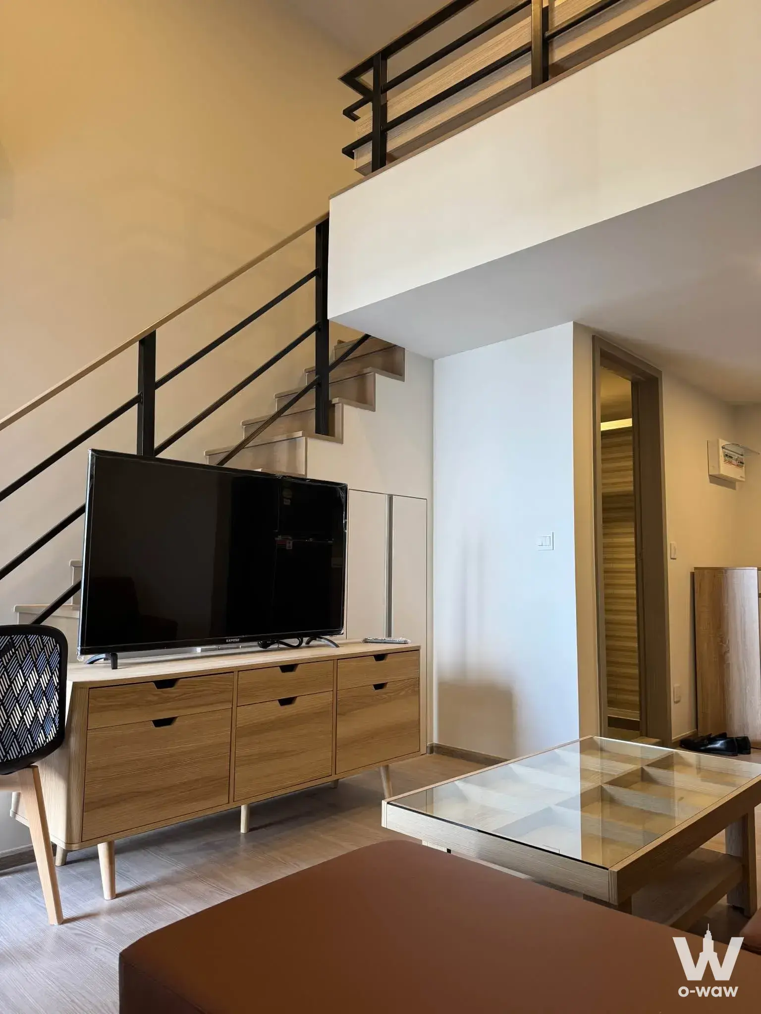 Modern loft living room with double-height ceiling and floating wood staircase in Aspire Sukhumvit-Rama 4