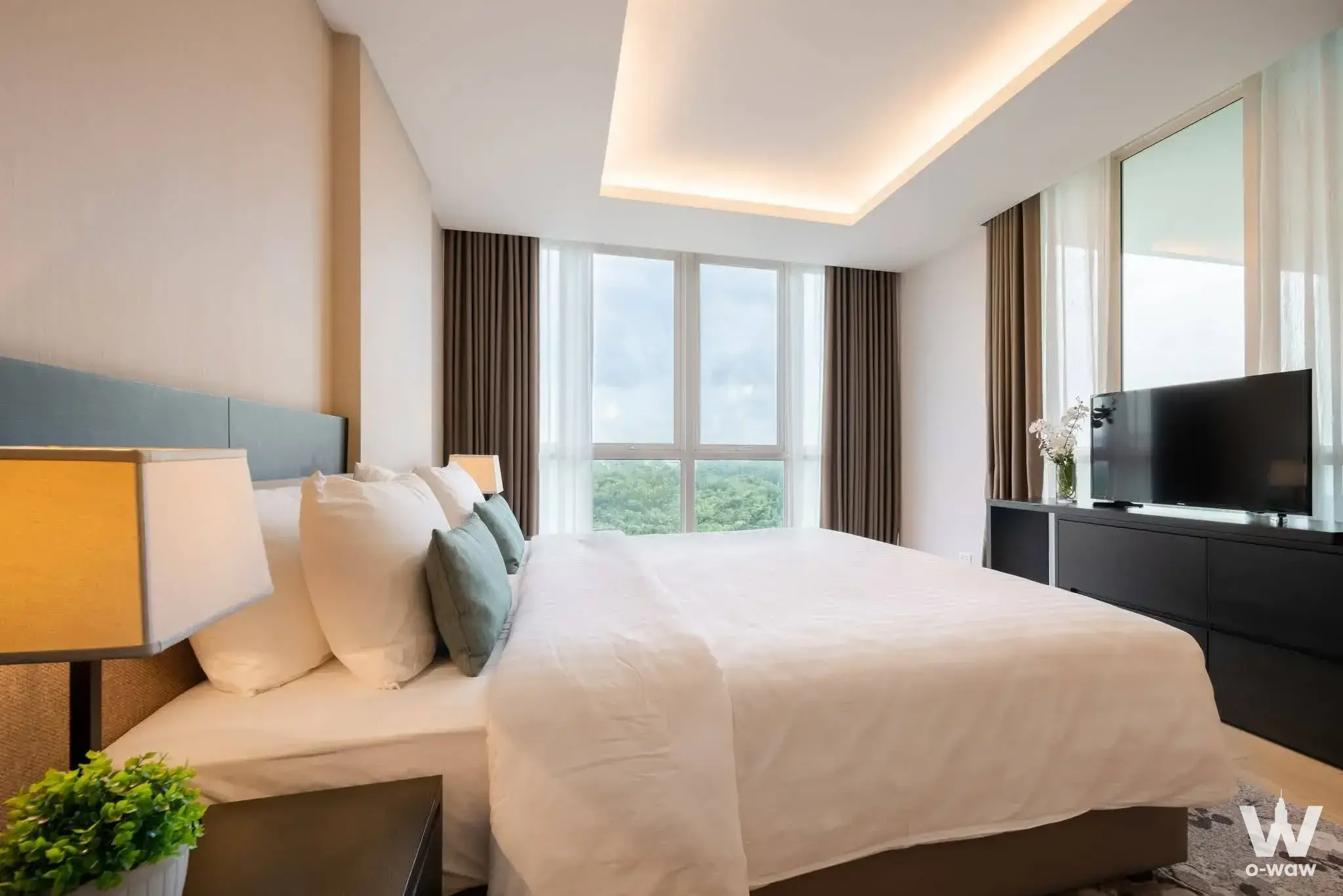 Luxury master bedroom for rent in North Park Place with teal accents, king bed, and lush green view
