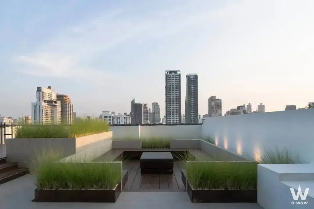 Open-air rooftop terrace with dark wood deck and concrete planters overlooking the Bangkok skyline from D.S. Tower 2