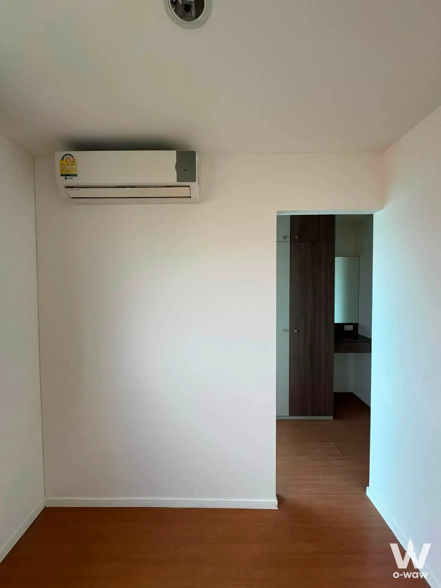 Lumpini Condo Town Ram Inthra 2-bed condo for sale features an empty room, white walls, and wood-look flooring