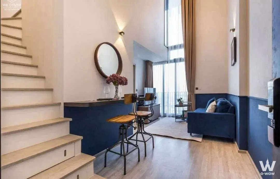 Loft living area with floating stairs and navy wainscoting in THE LINE Sukhumvit 71 condo for sale