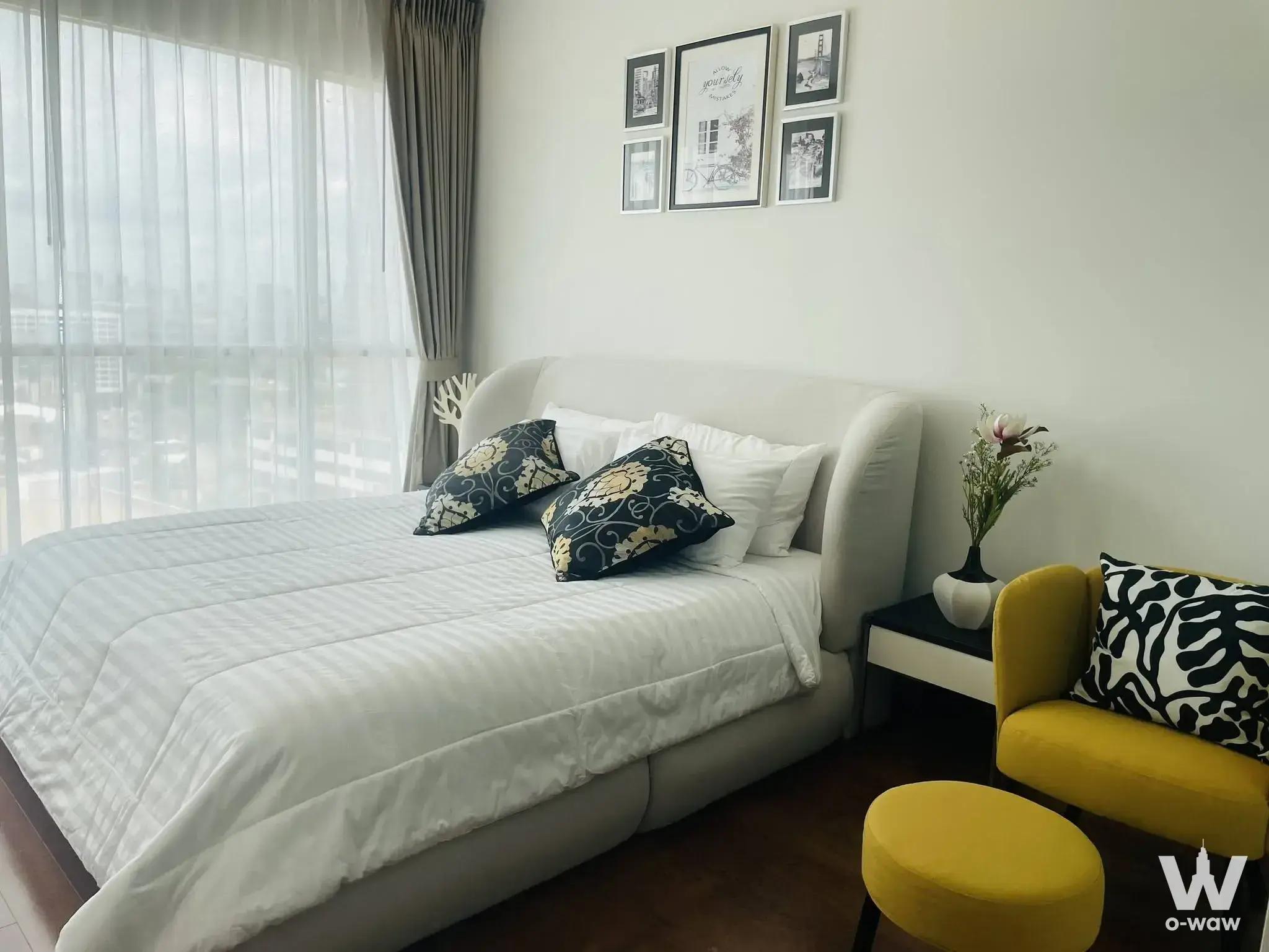 Queen bed with city skyline view and mustard armchair in a bedroom at The Address Chidlom