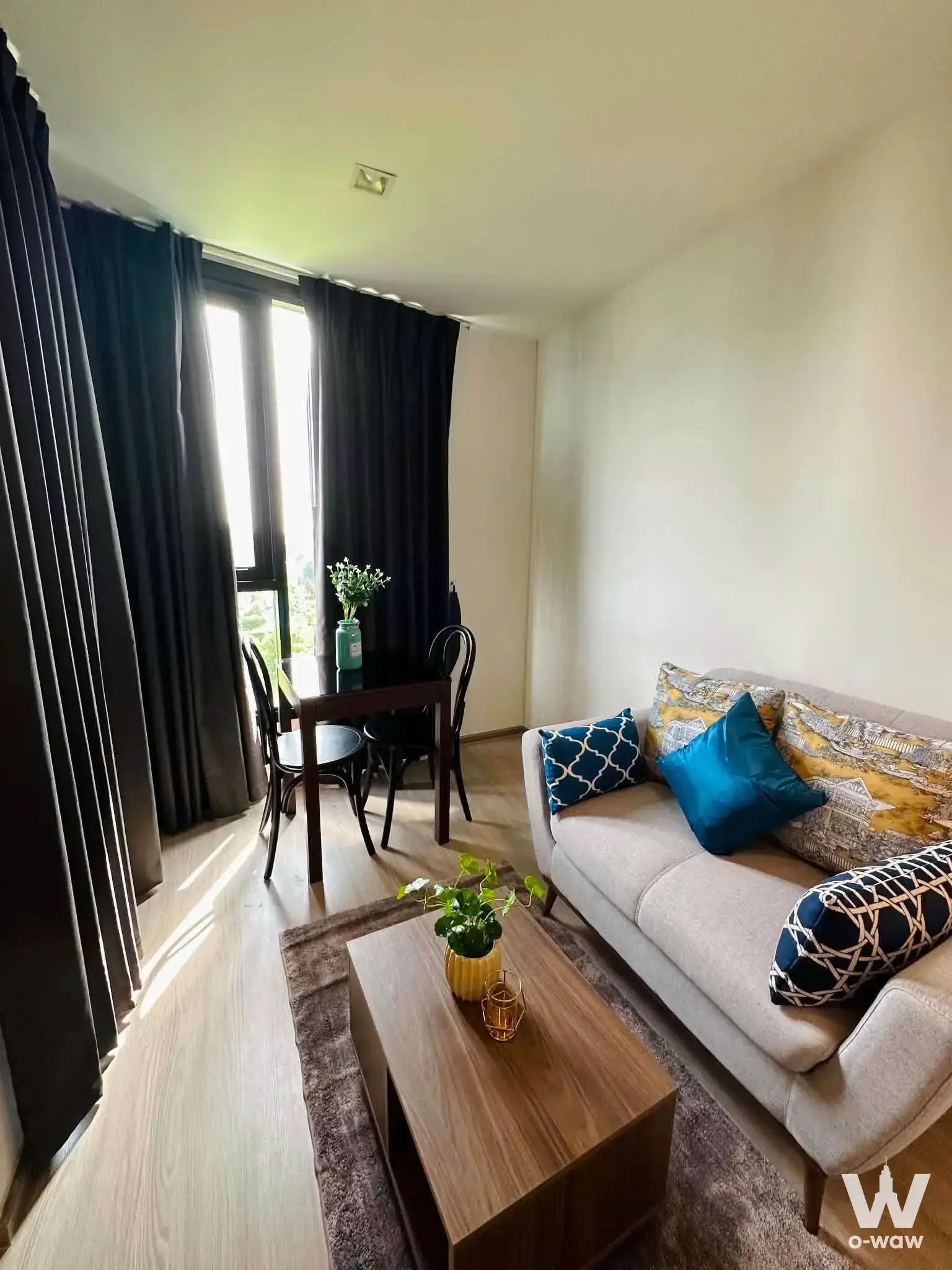 Living room with teal pillows and dining area in a 1-bed condo for rent at THE BASE Central Phuket