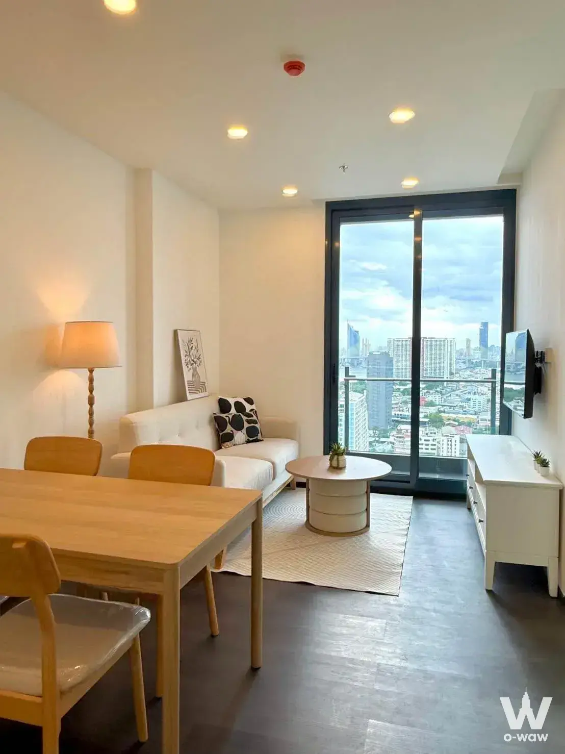 Sapphire Condominium living room with grey wood floors, Scandinavian furniture, and high-rise city views