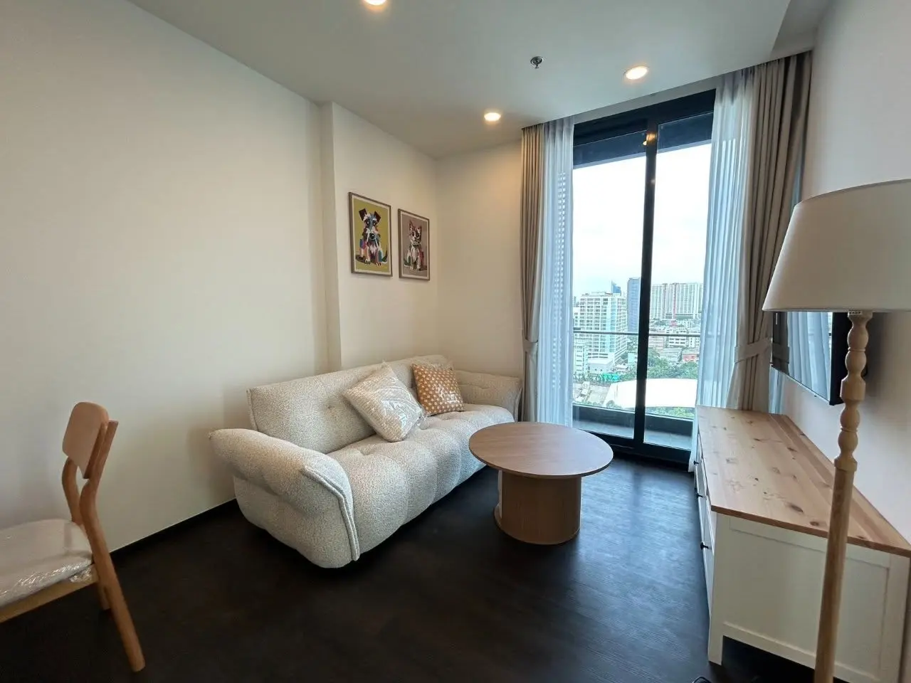 2-bed condo for rent in Sapphire Condominium featuring cream sofa, dog portraits, and balcony city views