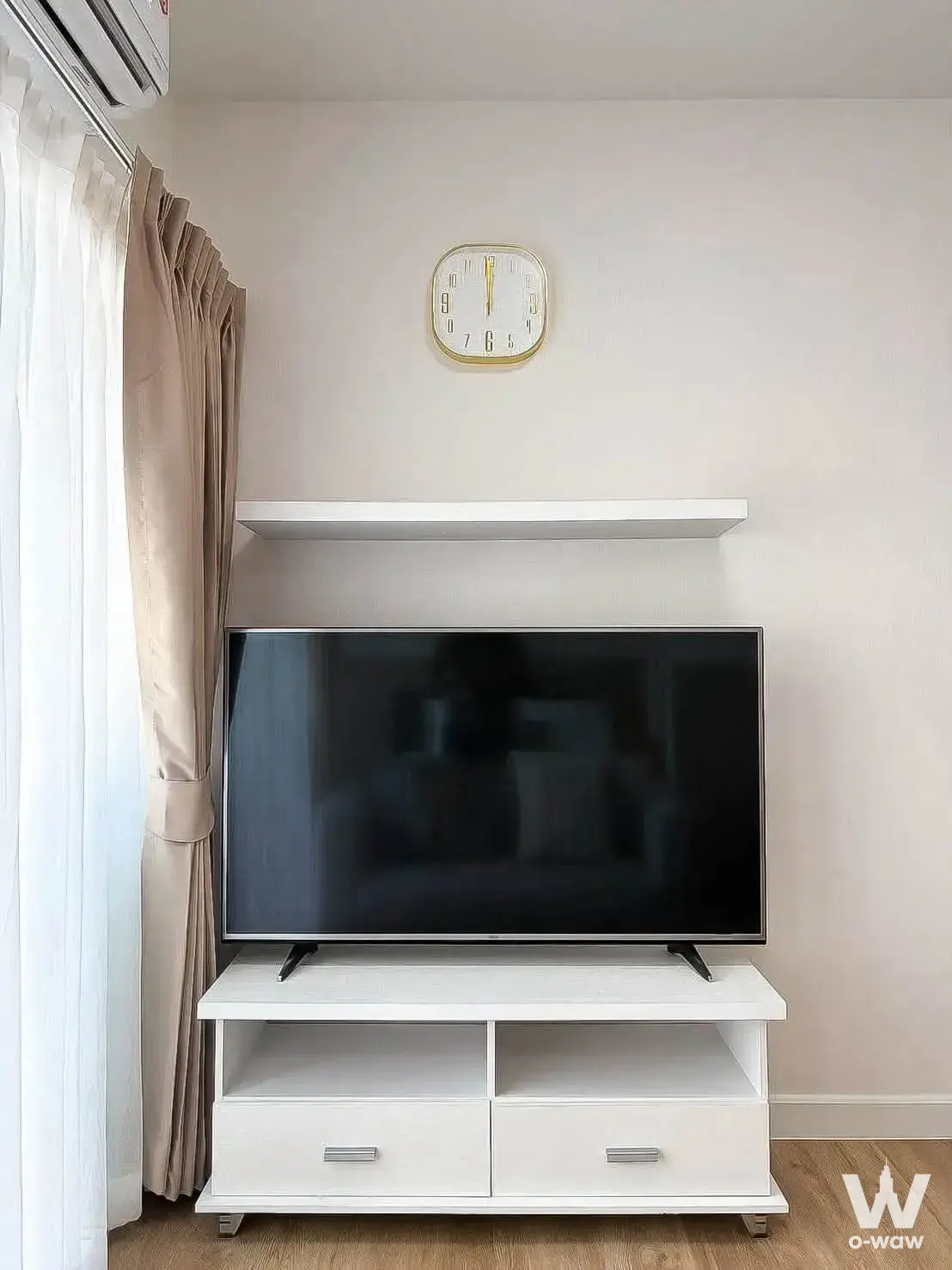 Space Condominium 1-bed living corner with TV console and beige curtains
