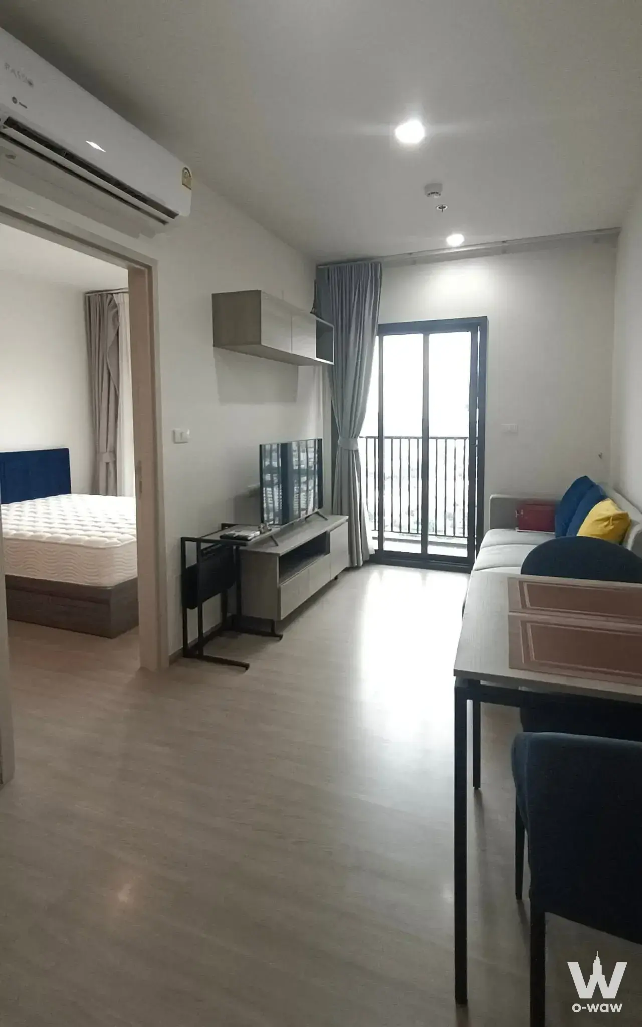 Open-plan studio with grey sofa, dining set, and balcony view available for rent at THE BASE Phetchaburi-Thonglor