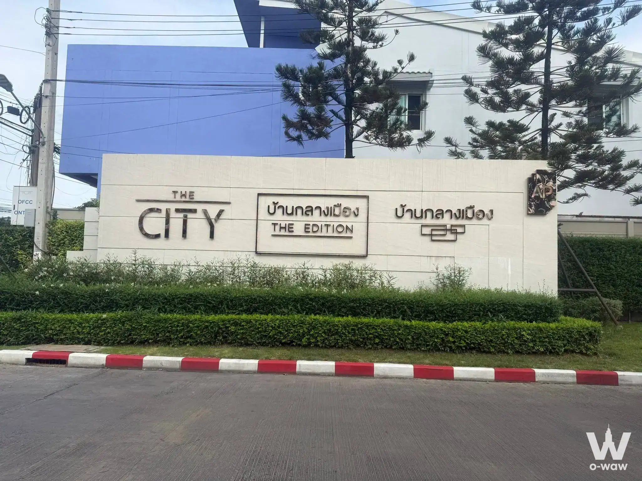 The City Edition townhouse entrance in Baan Klang Muang Srinakarin-Onnut with beige stone wall and manicured hedges