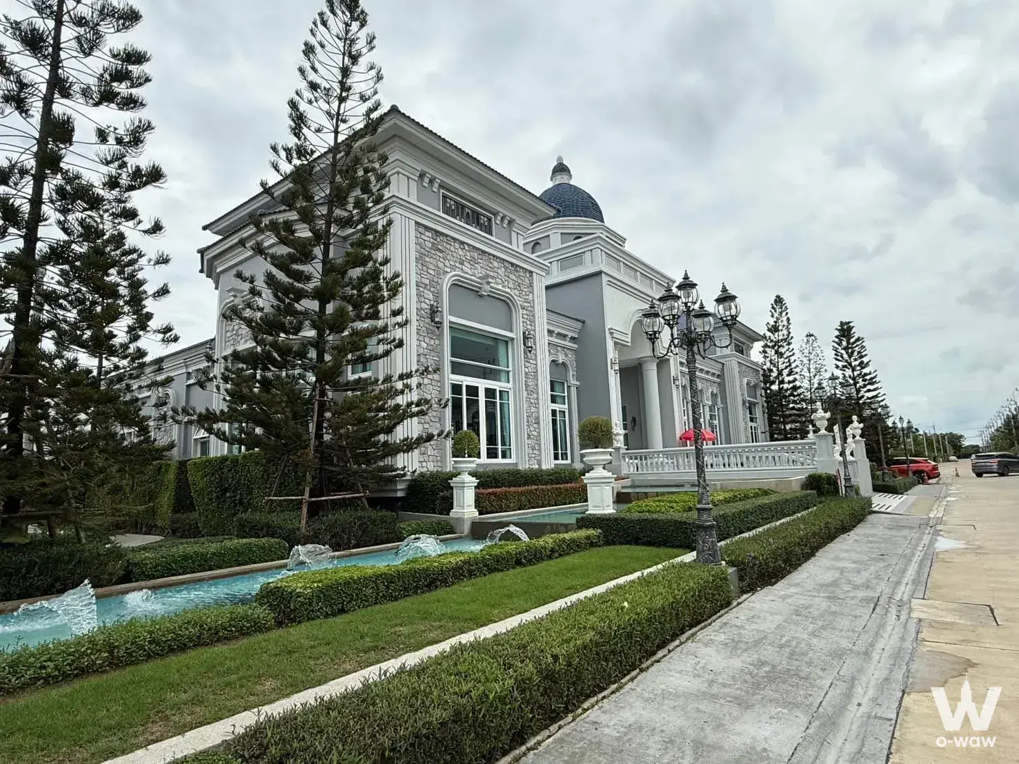 Neoclassical mansion exterior with grey stone facade, white columns, and a blue dome roof