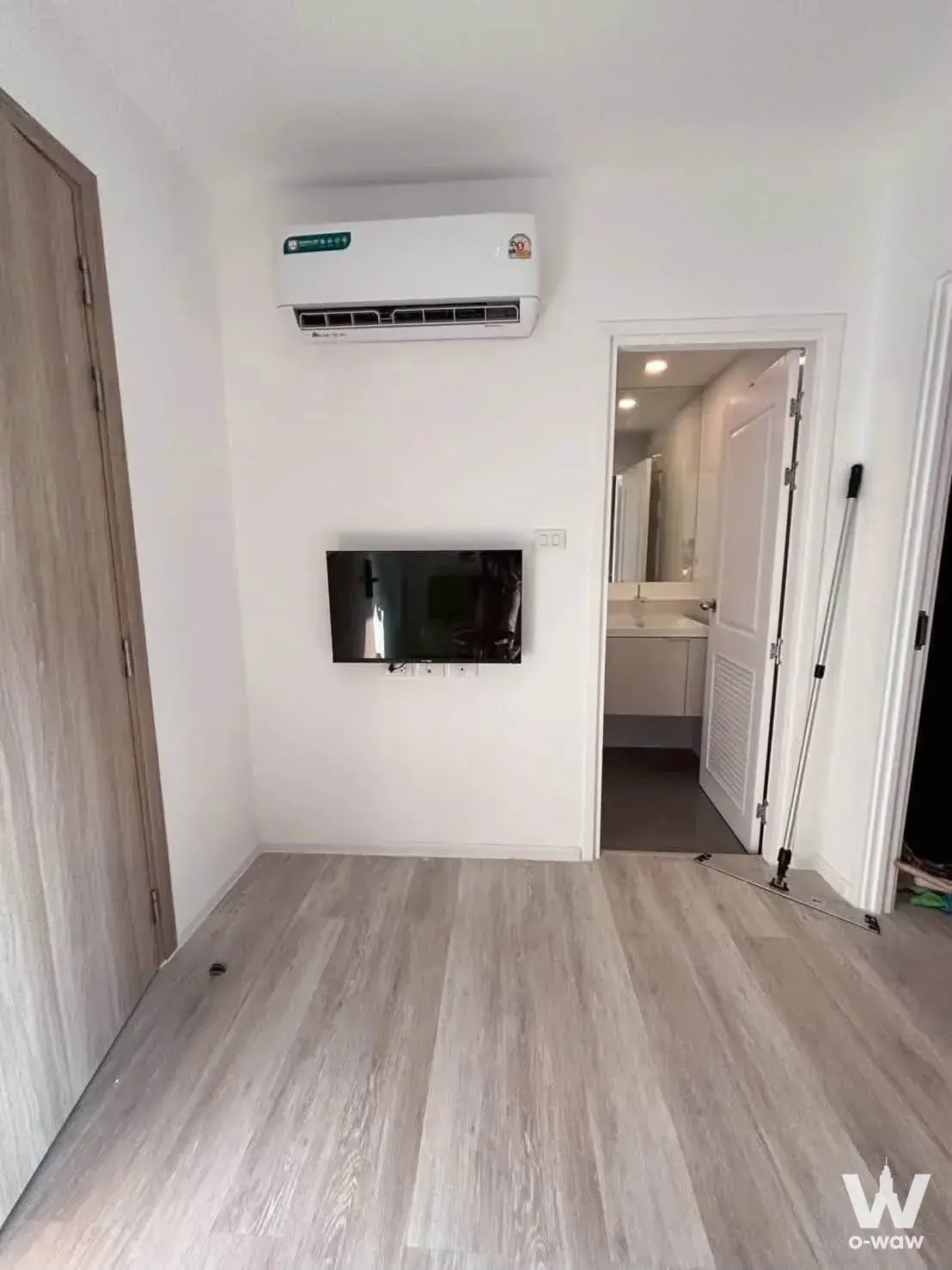 Empty studio with white walls and wood-look flooring in a 1-bed condo for sale at THE LINE Wongsawang