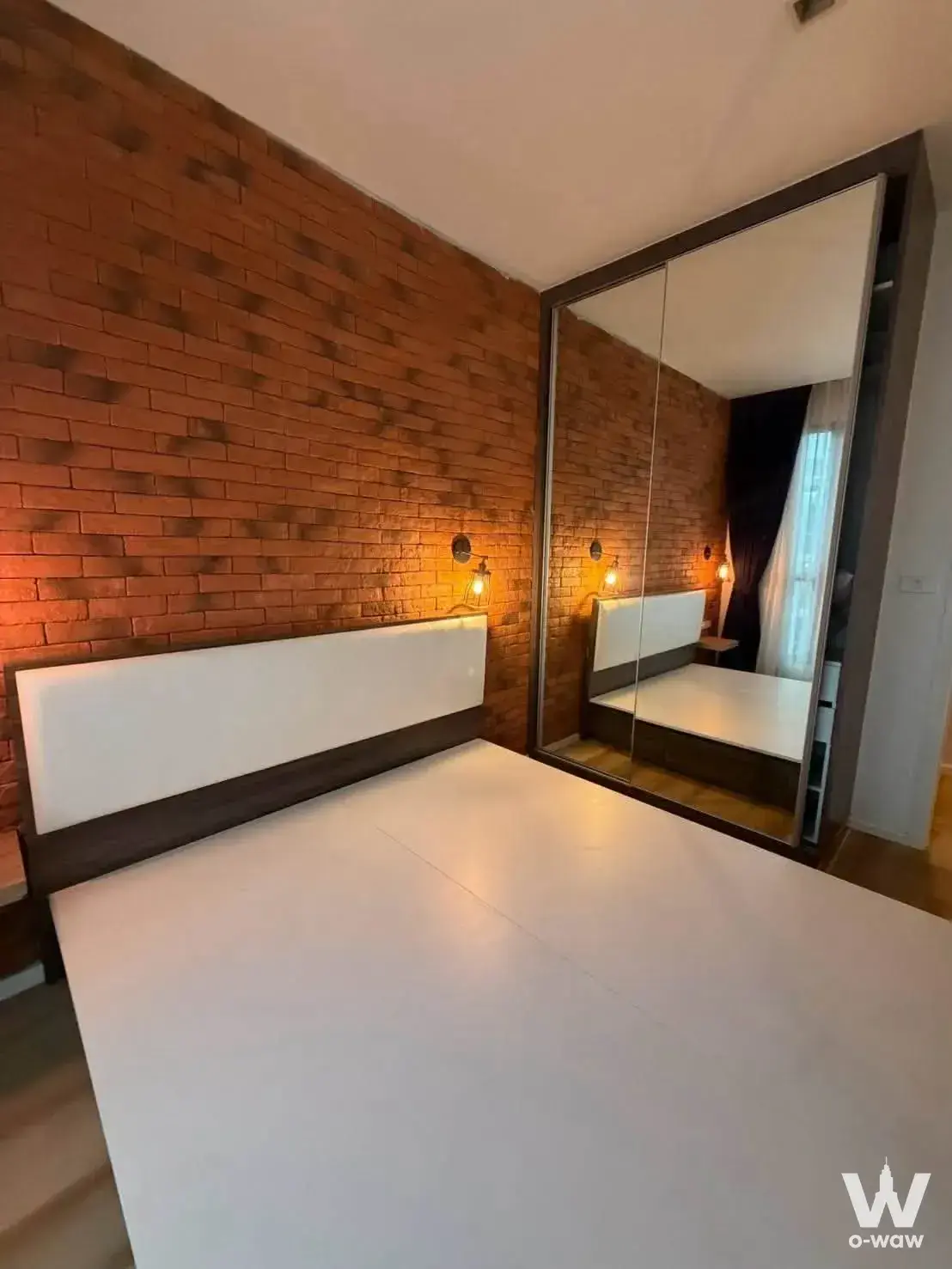 2-bed condo for sale in Quinn Condo bedroom with exposed red brick wall, Edison sconces, and mirrored wardrobe