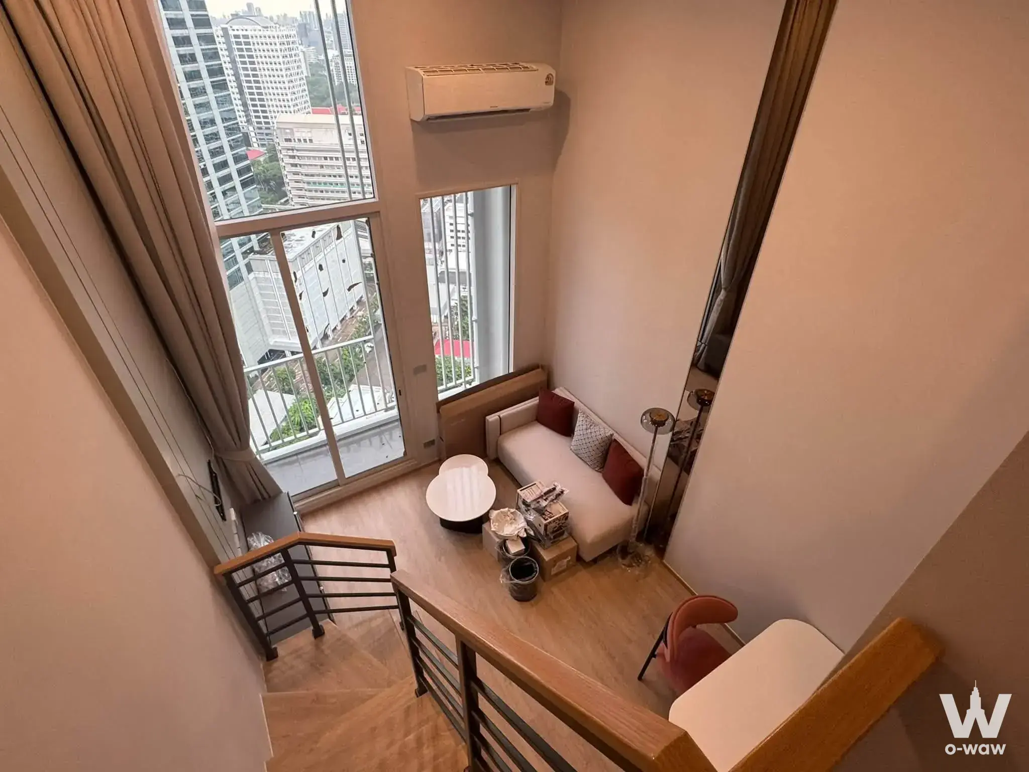 Loft living room in Culture Chula 1-bed rental featuring sofa, boxes, and staircase to upper level