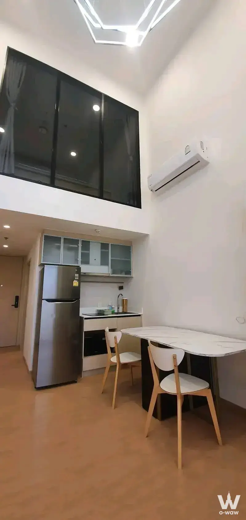 Open-plan loft in MARU Ekkamai 2 featuring mezzanine, kitchenette, and marble dining table