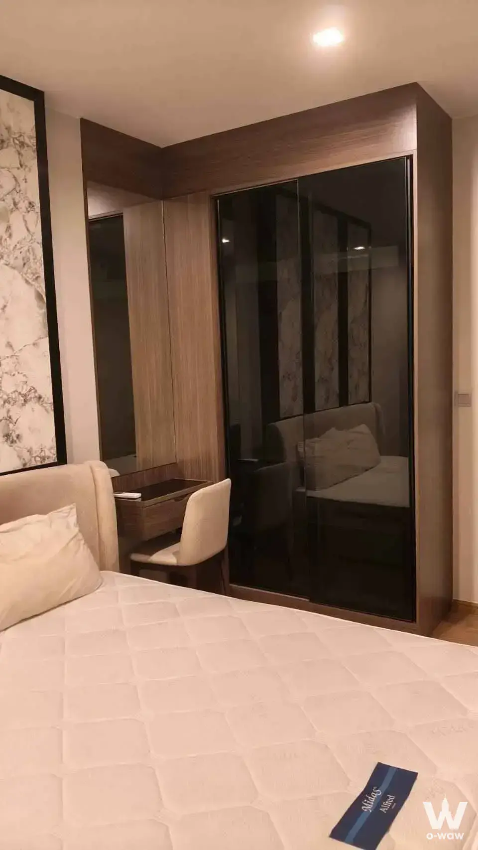 Bedroom in a 1-bed condo for rent at Q Prasarnmit featuring dark wood wardrobe and beige bed