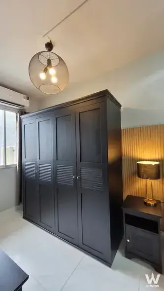 Bedroom in City Home Sukhumvit condo with large black louvered wardrobe and industrial wire cage light