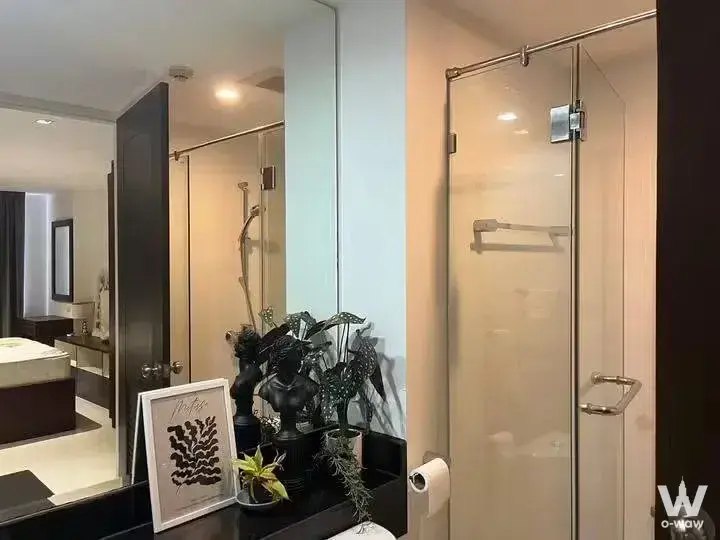 0-bed condo for sale in Golden Coast Siracha bathroom with glass shower, dark wood vanity, and large mirror