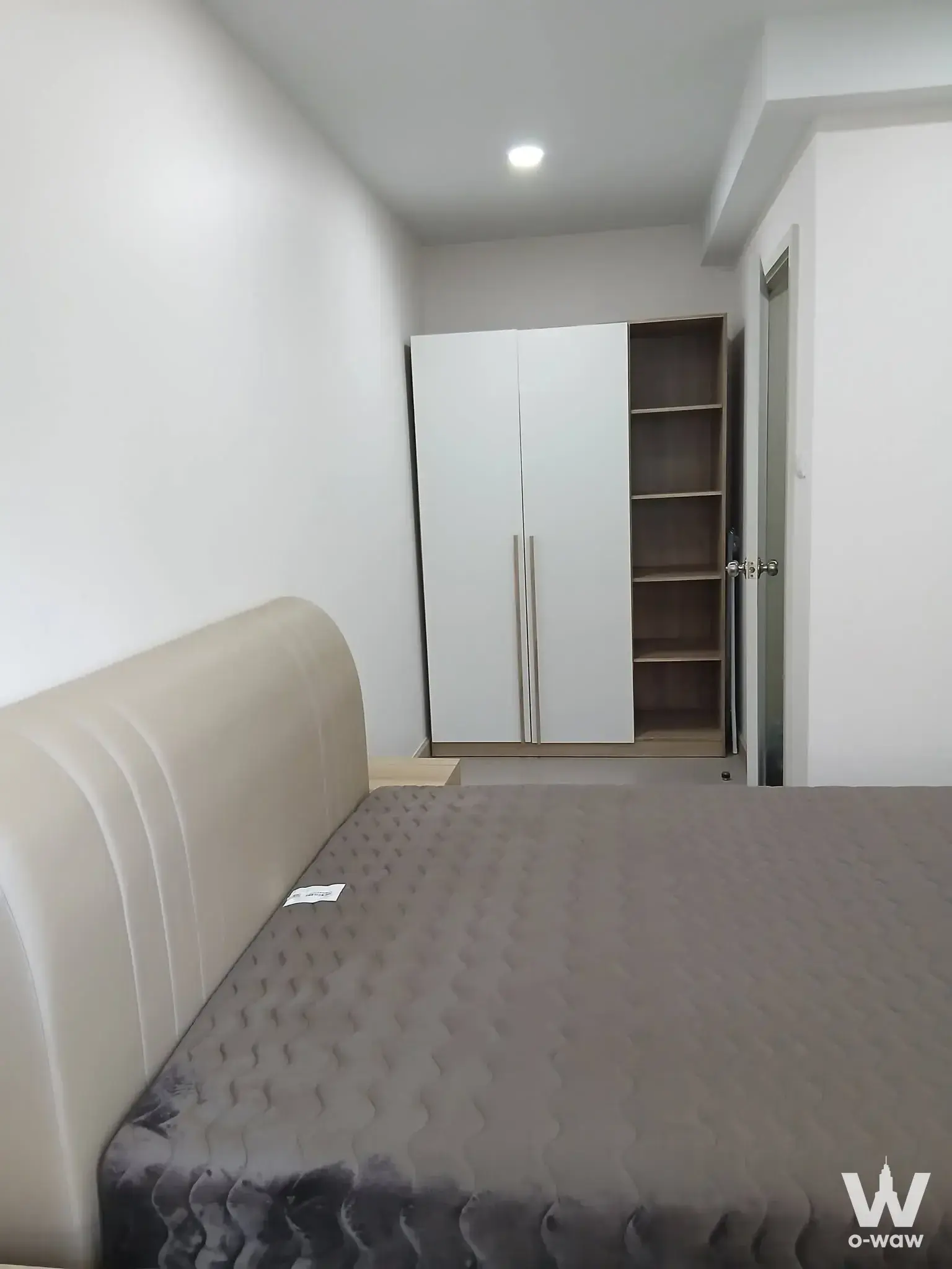 Minimalist 1-bed condo for sale in Supalai City Resort Charan 91 with beige upholstered bed and white wardrobe