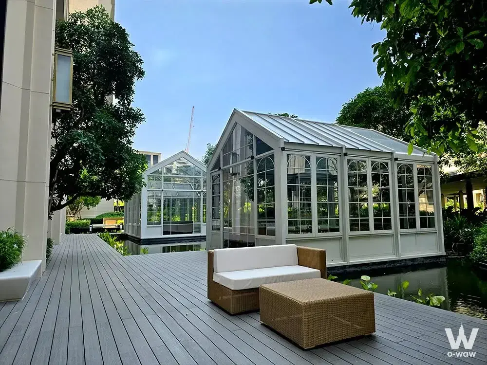 Terrace at The Aspen Tree Residences with wicker seating, glass greenhouse, and lily pad water feature