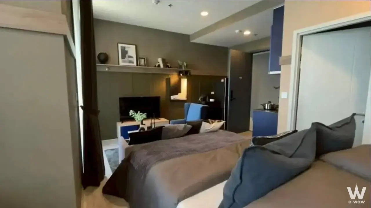 Studio bedroom in XT Ekkamai condo with grey duvet, blue accents, and compact modern layout