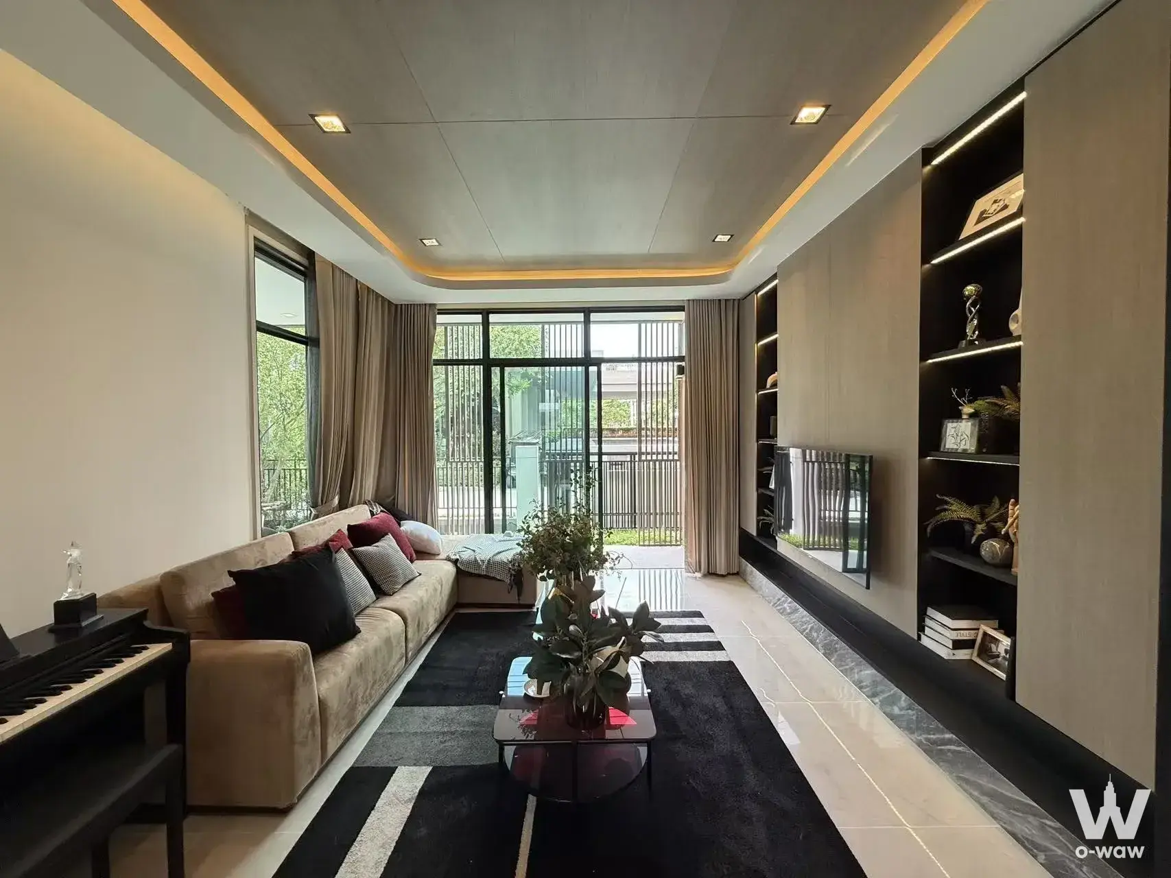 Spacious living room in a 4-bed Grand Bangkok Boulevard house featuring a beige sectional and glass balcony doors