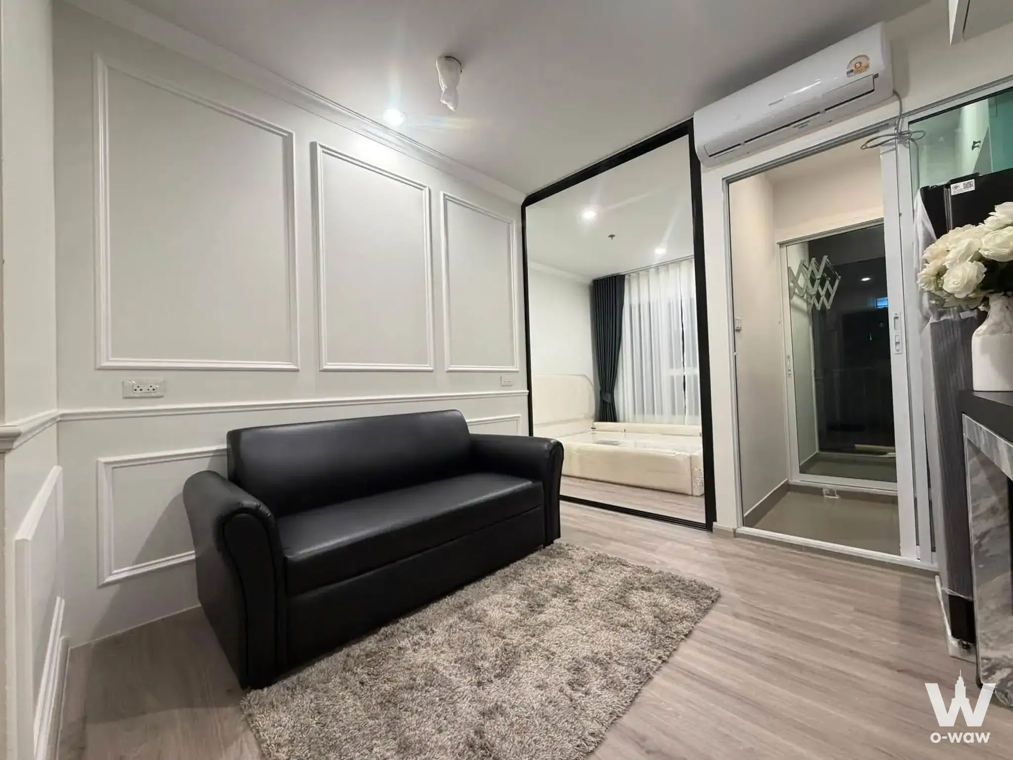Regent Home Bangna studio living room with black leather sofa and large framed mirror
