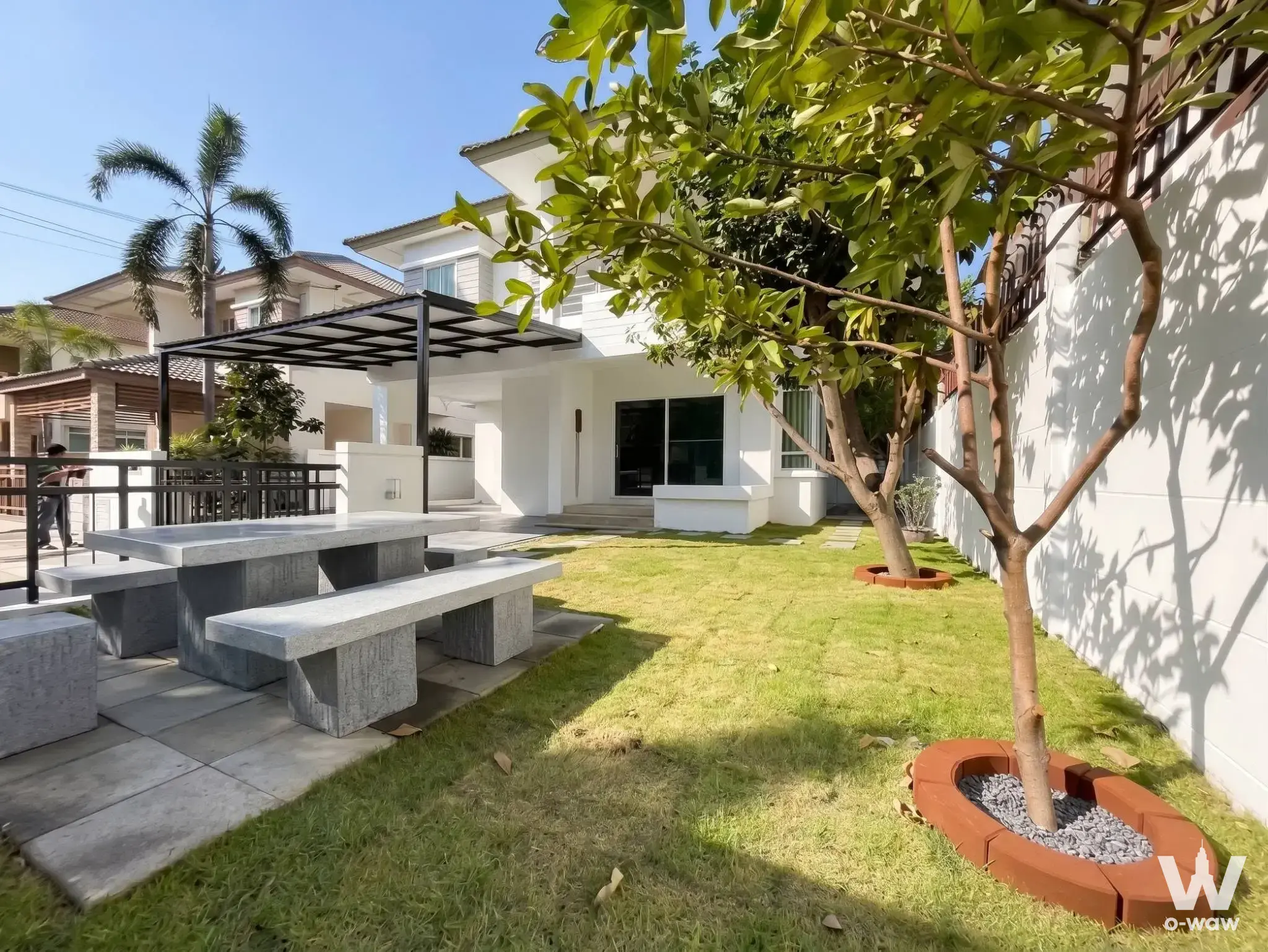 The backyard of a 3-bed house for rent at Saransiri Ramintra 2 has a stone dining table under a black metal pergola