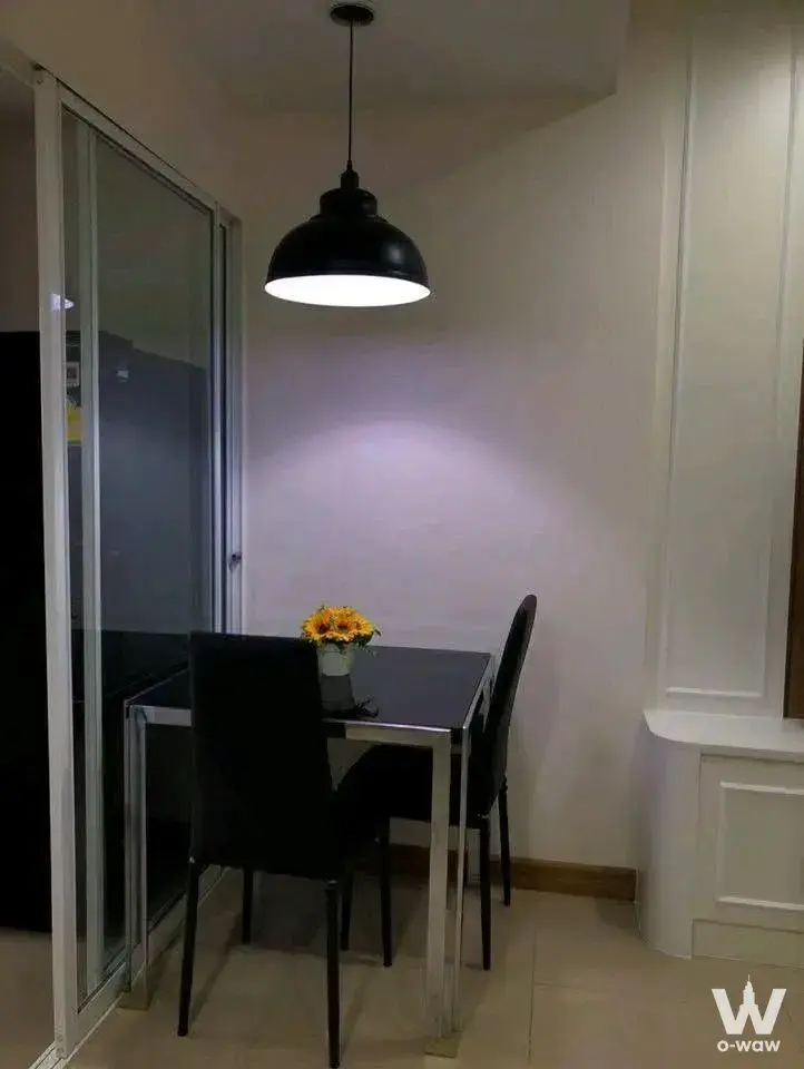 Compact dining nook in Supalai Wellington II condo featuring black glass table and warm pendant light