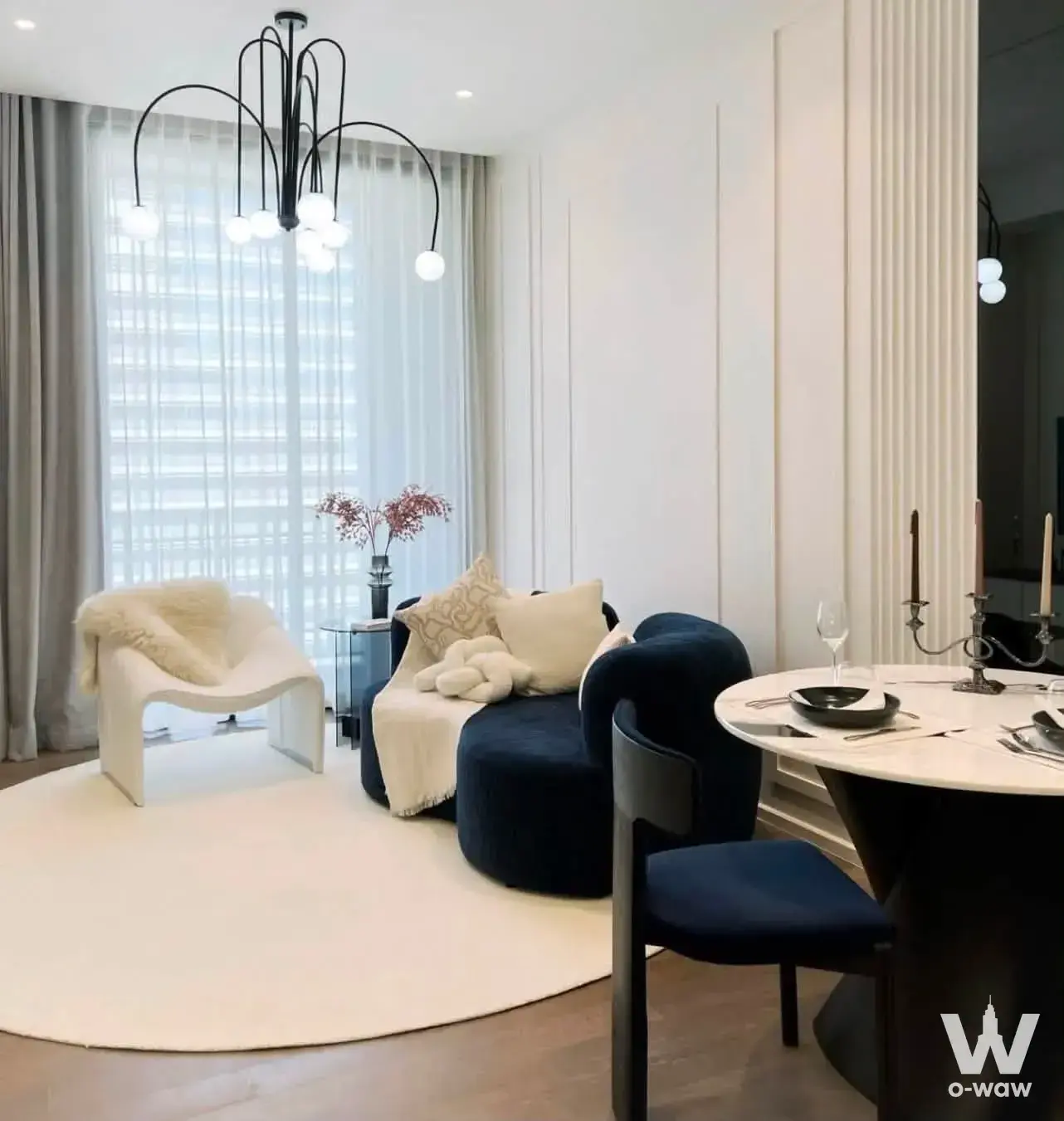 MUNIQ Lang Suan living room with navy velvet sofa, marble dining table, and floor-to-ceiling city views