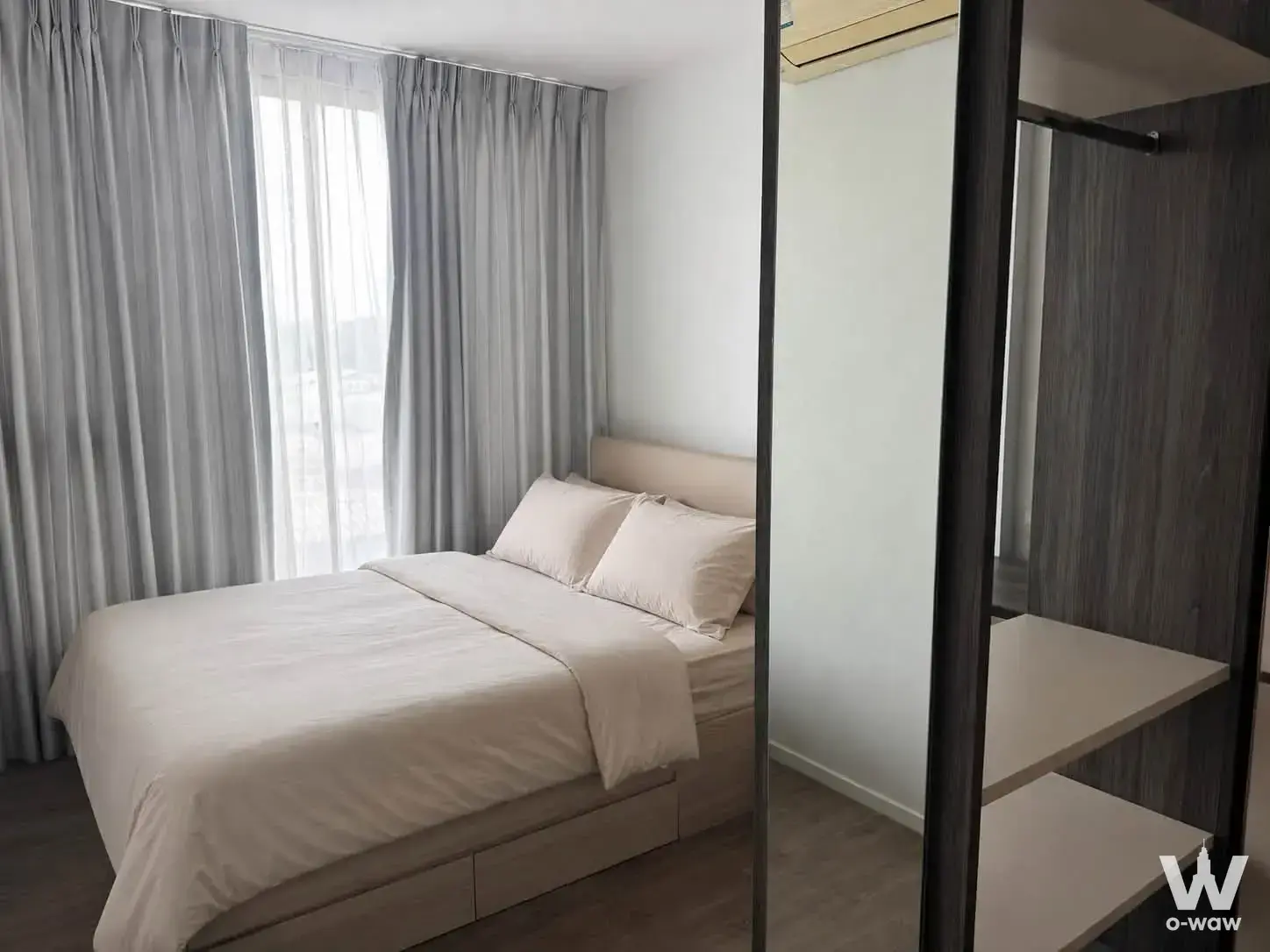 Queen bed beside a built-in wardrobe unit with floor-to-ceiling window in a 1-bed condo at The Nest
