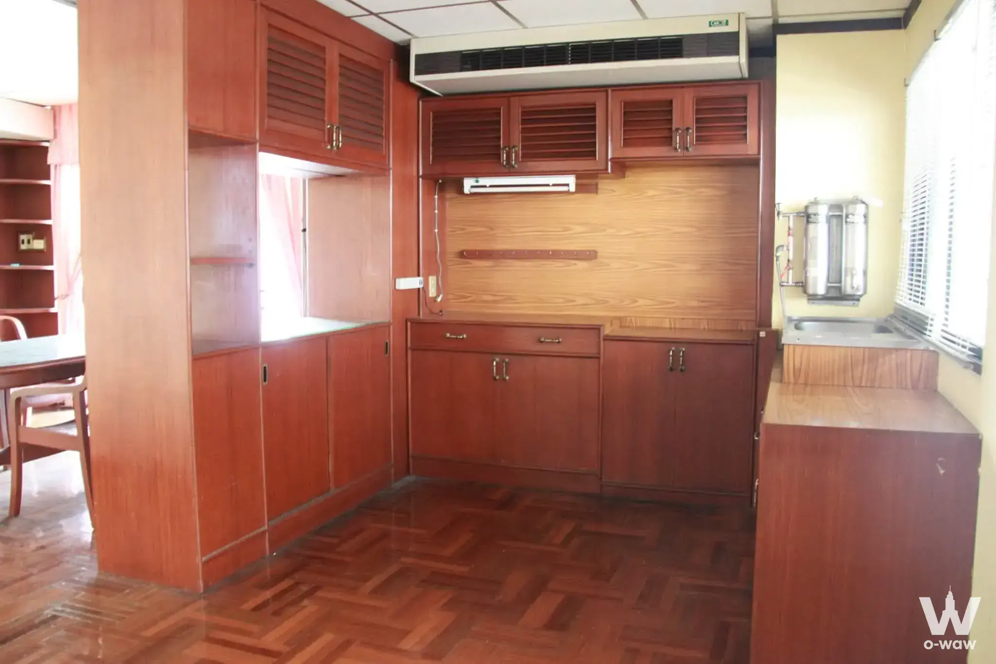 Vintage 1-bed condo interior in Fair Tower featuring reddish-brown louvered cabinetry and herringbone parquet flooring