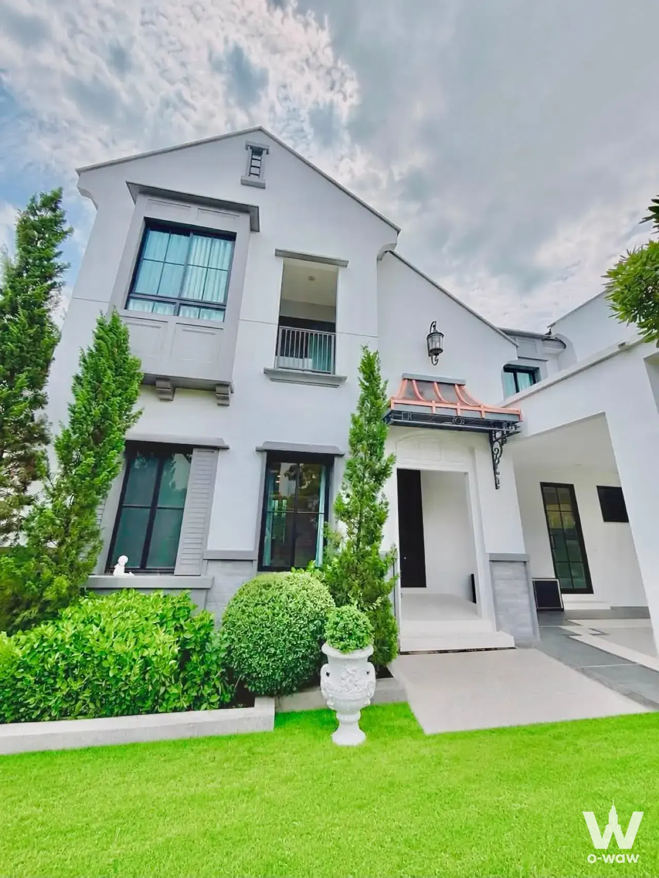 Two-story white house for sale in Nantawan Rama 9 with copper canopy, black-framed windows, and manicured lawn