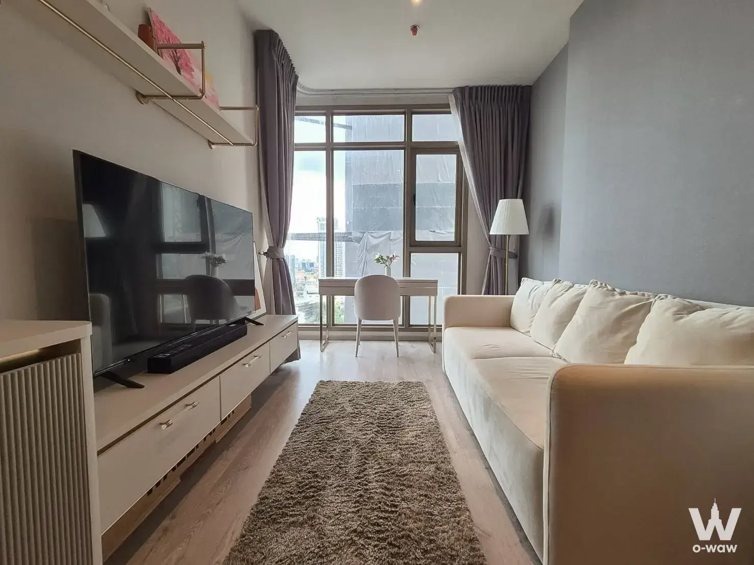Modern 1-bed condo living room in Rhythm Ekkamai Estate with cream sofa and city view