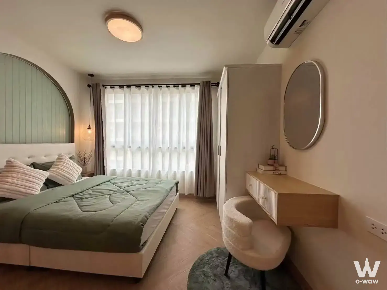 Sage green quilted bed with arched mint headboard in 1-bed condo for sale at dcondo Creek Phuket