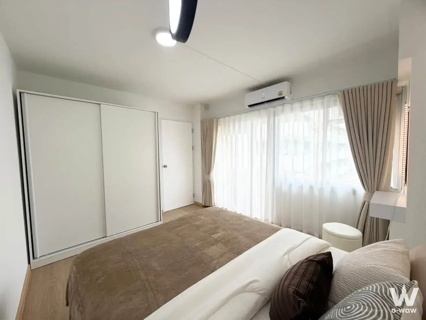 Minimalist master bedroom in Family Park Condominium with white sliding-door wardrobe and neutral color palette