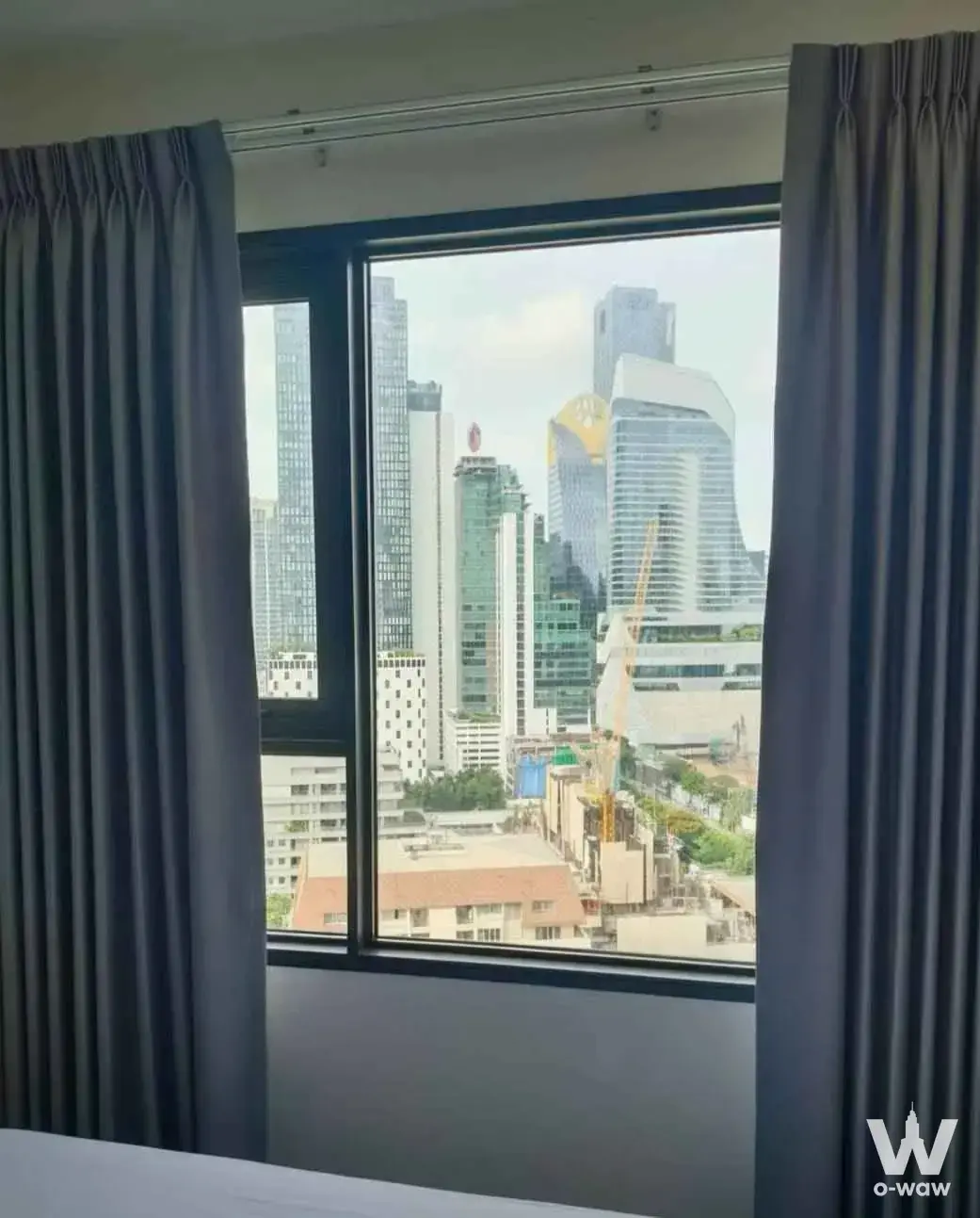 High-floor bedroom at Life One Wireless offering an unobstructed view of Bangkok skyscrapers through large windows