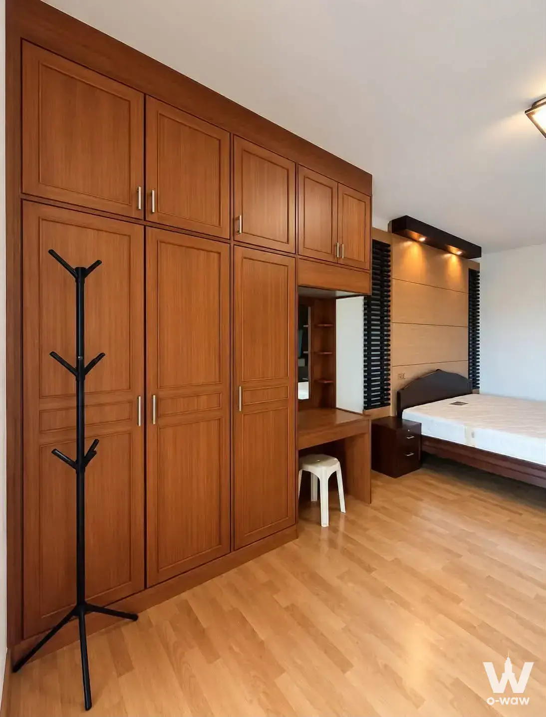 The bedroom in a 2-bed condo for rent at Cityhome Ratchada-Pinklao A6 has a built-in wooden wardrobe wall and vanity desk