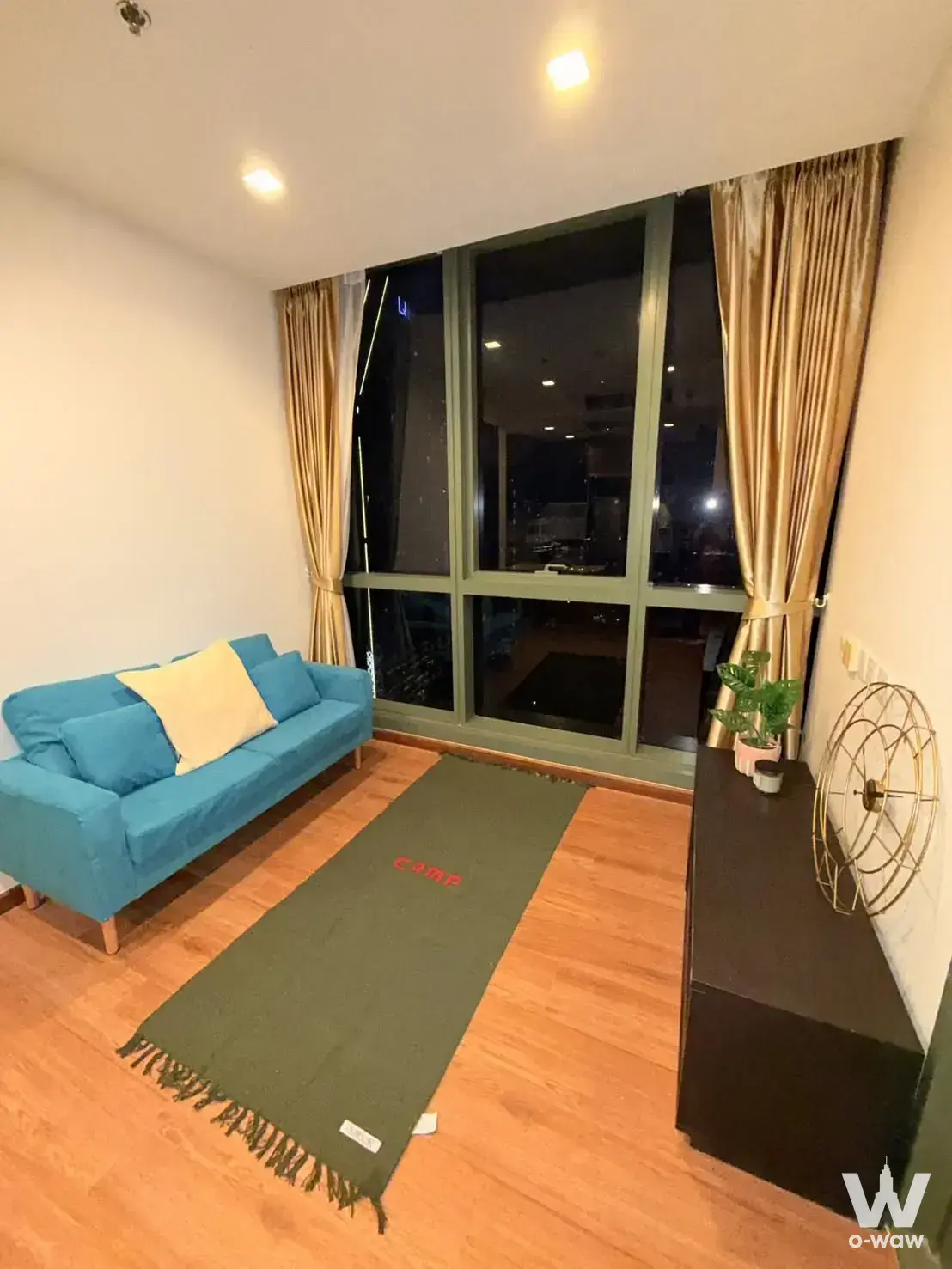 The living room in a 1-bed WISH Signature Midtown Siam condo has a teal sofa and a night city view