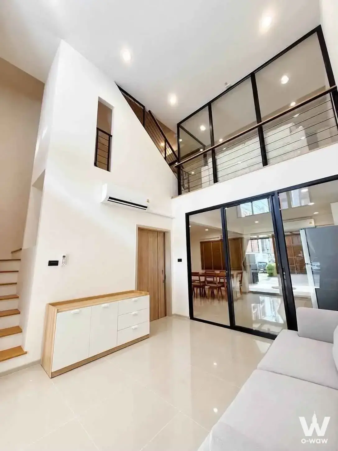 Modern townhouse living area with glass partition and mezzanine at Shizen Phatthanakan 32