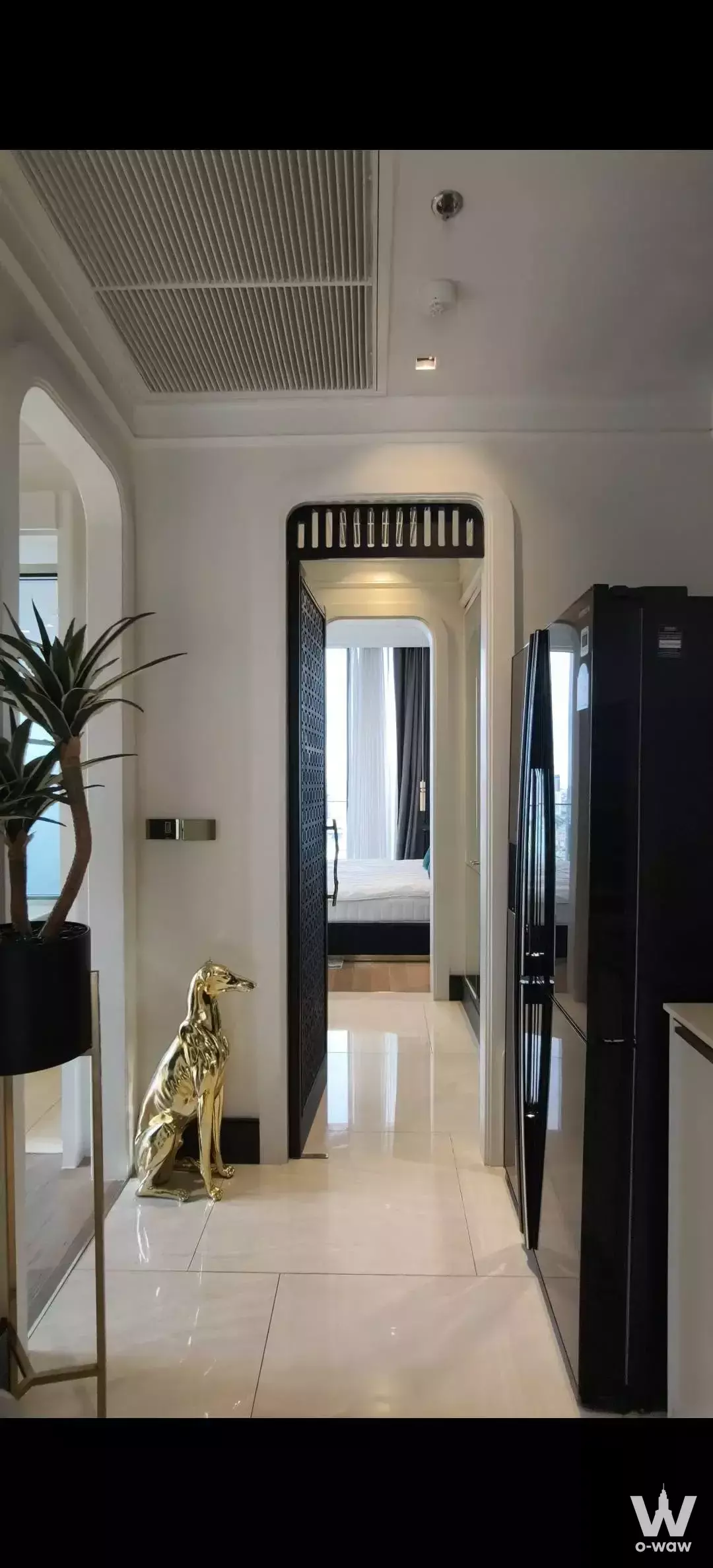 Cream-tiled hallway in Ashton Silom condo featuring arched doorways and gold accents