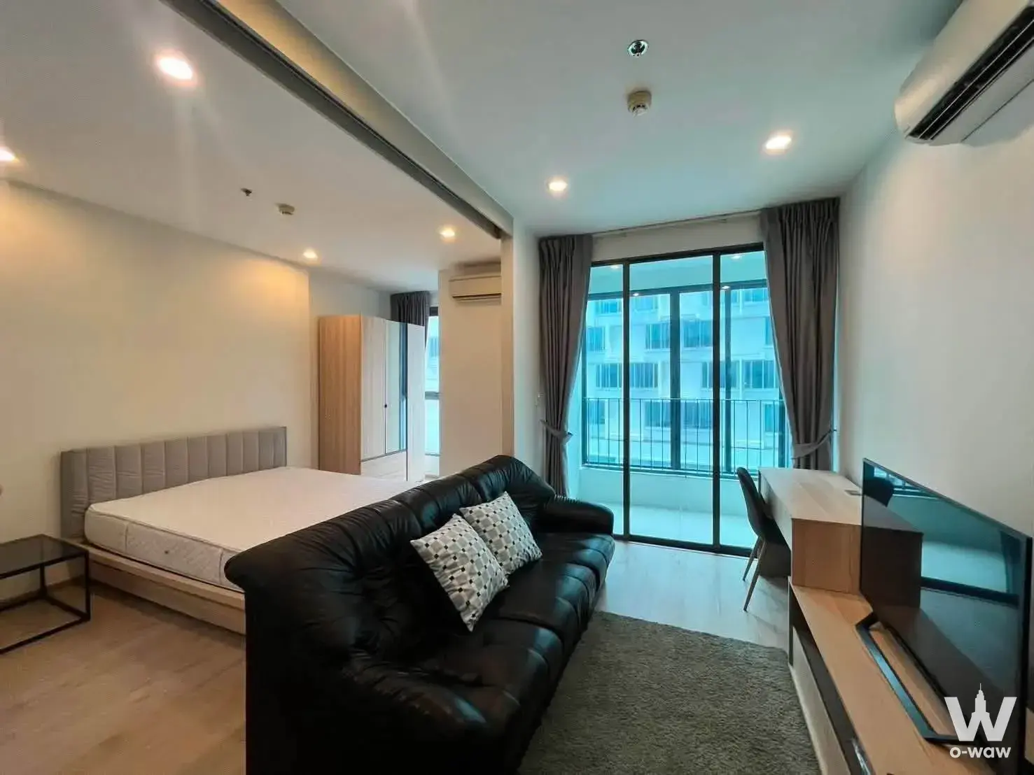 Furnished 1-bed condo in Ideo Q Chula-Samyan featuring a queen bed, black leather sofa and floor-to-ceiling balcony doors