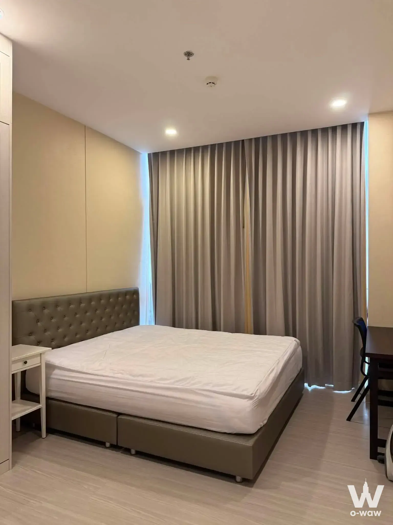 Premier Condominium 1-bed rental bedroom has a leather bed, nightstand, desk and full-wall sheer curtains